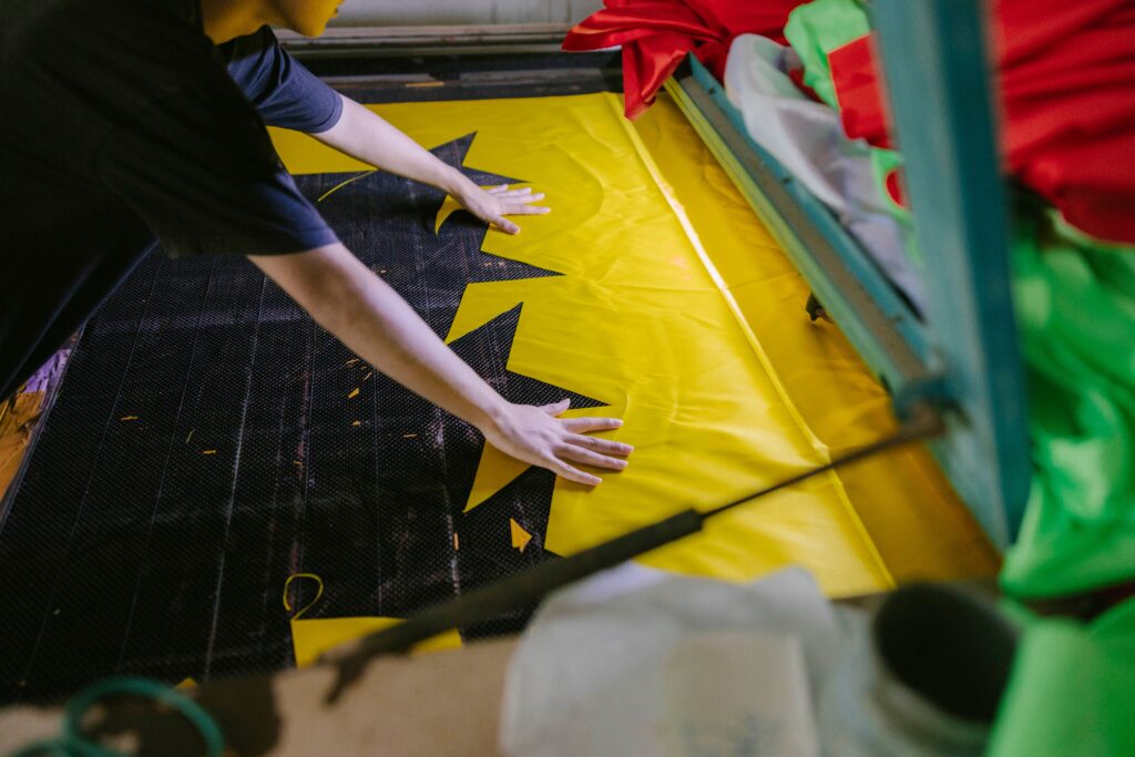A person laying out bright fabric in a workshop setting.