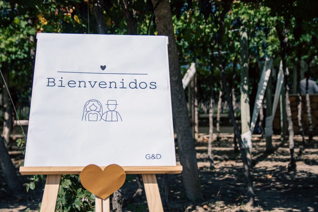 Welcome sign for outdoor wedding with trees and heart decor.