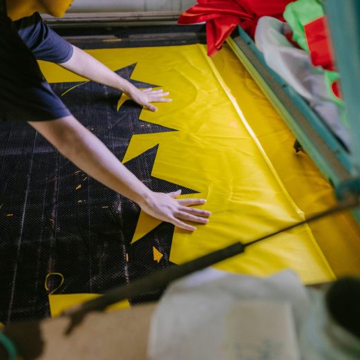A person laying out bright fabric in a workshop setting.