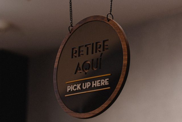 A minimalist hanging sign indicating order pickup in a store setting.