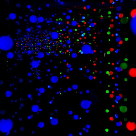 Abstract display of vivid blue, red, and green light spheres in dark space.