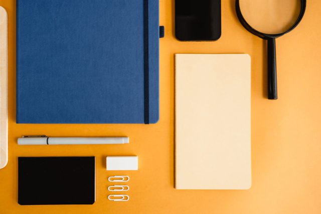 Artistic flat lay of diverse office stationery on a vibrant yellow background.
