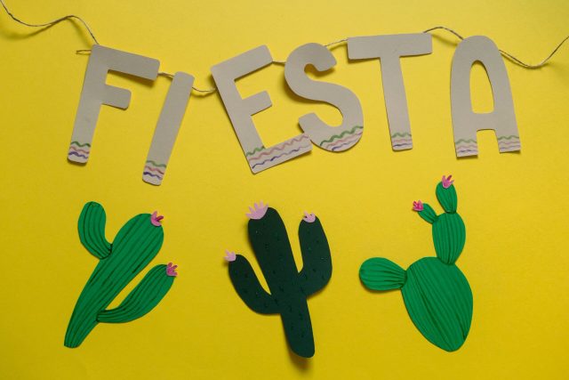 Festive decoration for a fiesta with vibrant cactus paper cutouts on a yellow background.